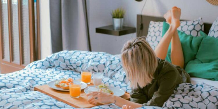mujer acostada en la cama con desayuno