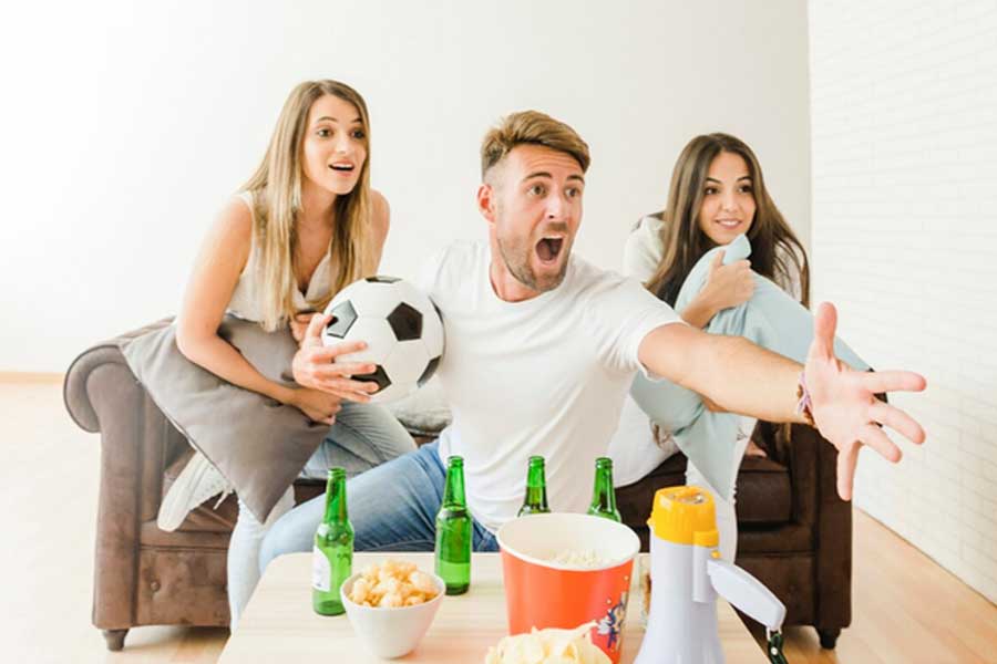 hombre y mujeres en casa celebrando viendo la tv fútbol