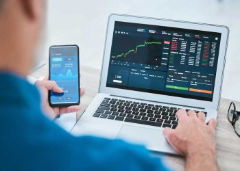 hombre con app y laptop sitio de operaciones financieras