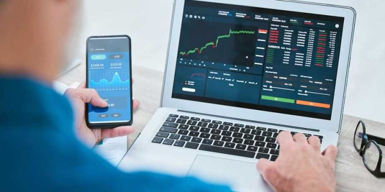 hombre con app y laptop sitio de operaciones financieras