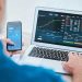 hombre con app y laptop sitio de operaciones financieras