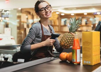 Feliz mujer cajera escaneando artículos de supermercado