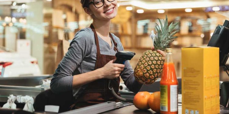Feliz mujer cajera escaneando artículos de supermercado