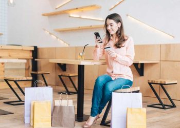 Mujer con tarjeta de crédito usando teléfono inteligente en café