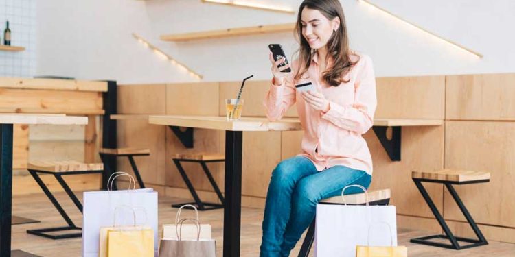 Mujer con tarjeta de crédito usando teléfono inteligente en café