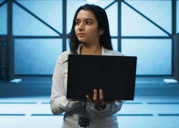 Mujer trabajando en industria TI sosteniendo una laptop