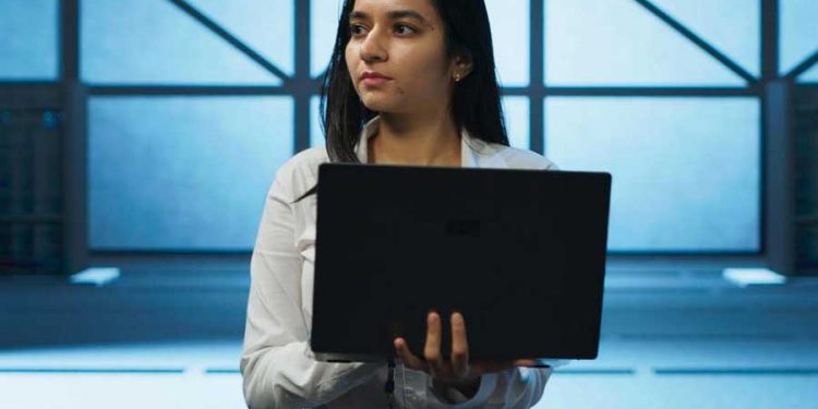 Mujer trabajando en industria TI sosteniendo una laptop