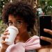 Tendencias de consumo mujer tomando café mientras revisa el celular