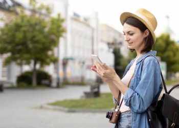 mujer viajera con sombre buscando en el teléfono móvil