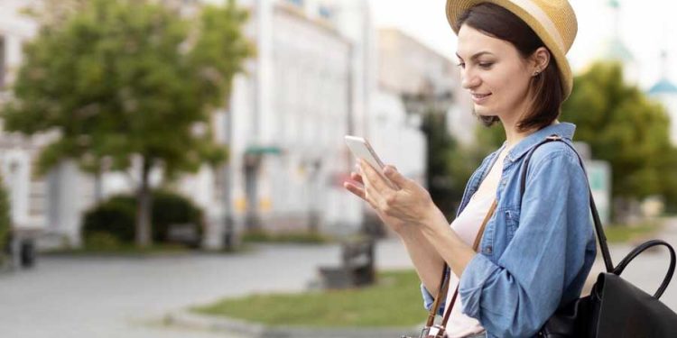 mujer viajera con sombre buscando en el teléfono móvil