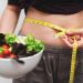 mujer midiendo su abdomen con comida saludable en un bowl