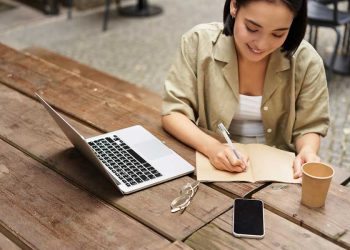 joven mujer trabaja o estudia en linea con una laptop