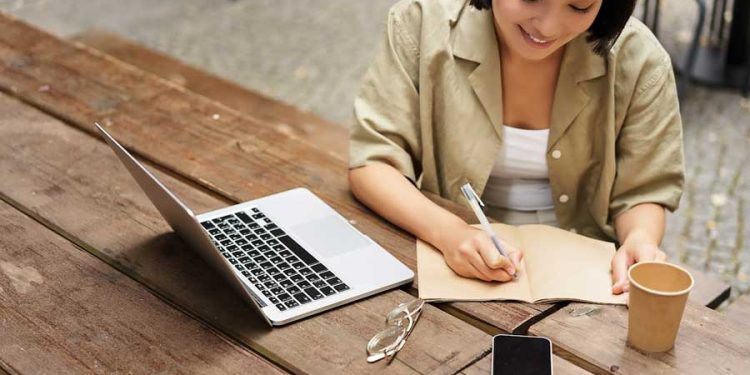 joven mujer trabaja o estudia en linea con una laptop
