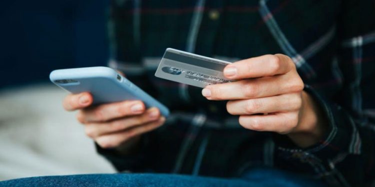 Hombre compra online con tarjeta de credito con smartphone