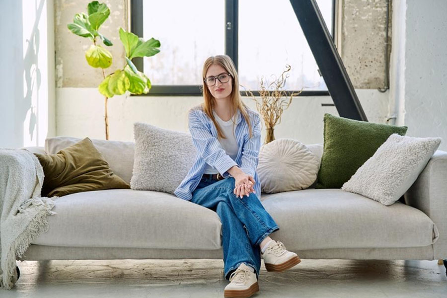Joven sentada en un mueble sillón blanco cómodo