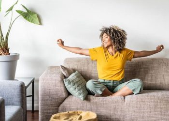 Muje con camisa amarillar sentada en un sillón cómodo